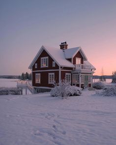 a red house is covered in snow at sunset