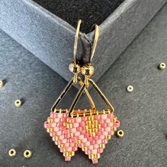 a pink and yellow beaded pendant on a black surface