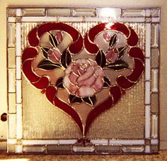 a heart shaped stained glass window with a rose on it