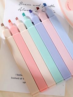 six pastel colored crayons are lined up on top of a piece of paper