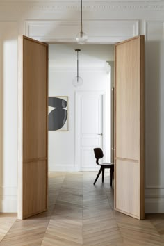 an open door leading to another room with a chair and artwork on the wall behind it