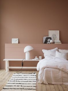 a white bed sitting in a bedroom next to a wooden table with a lamp on top of it