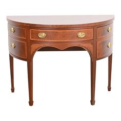 an oval wooden table with two drawers on one side and gold handles on the other