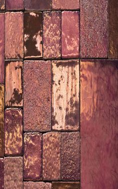 an old brick wall that has been painted purple and gold with rust on the surface