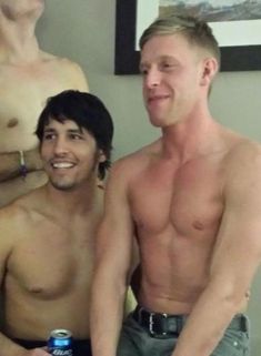 two men standing next to each other with no shirts on