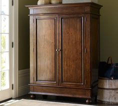 a wooden cabinet with two vases on top of it in front of a door