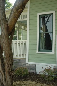 a house with a tree in front of it and a sign on the side of the house