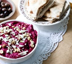 there is a bowl of hummus and pita bread on the table