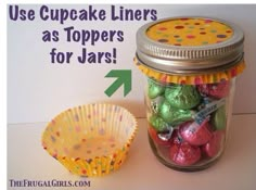 a jar filled with lots of candy sitting next to a cupcake liner on top of a table