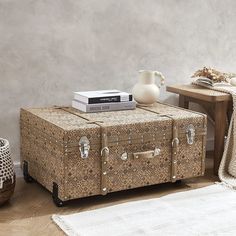 an old trunk sitting on top of a wooden floor next to a table with a vase