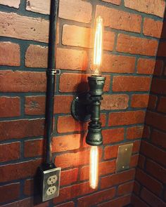 a light that is on the side of a brick wall next to a metal pipe