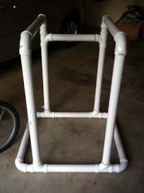 a bicycle is parked in the garage next to a white bike rack with pipes on it