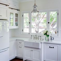 a kitchen with white cabinets and an old fashioned refrigerator freezer next to the sink