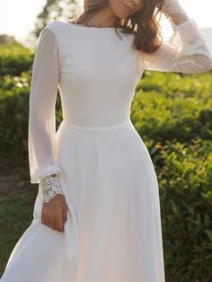 a woman in a white dress posing for the camera with her hands on her head