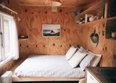 a bed in a room with wooden walls and shelves on the wall next to it