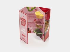 an open box with food inside on a white surface and in the background is a paper cut out