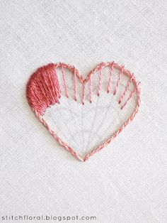 a heart shaped piece of yarn on top of a white table cloth with red thread