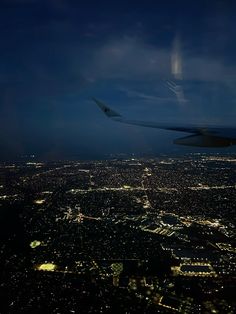 an airplane wing flying over the city lights at night