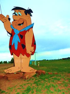 a large cartoon character standing on top of a lush green field