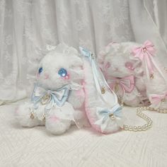 two white stuffed animals sitting next to each other on a bed covered in white fabric