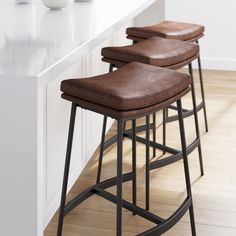 three brown stools sitting on top of a counter next to a white countertop