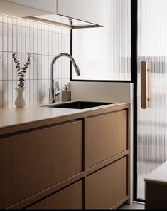 a modern kitchen with wooden cabinets and white tile backsplashing, stainless steel faucet over the sink