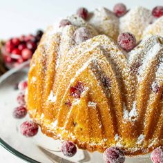 a bundt cake covered in powdered sugar and cranberries on a plate