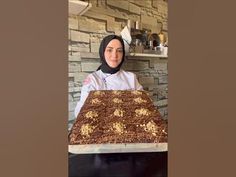 a woman in hijab holding a large cake