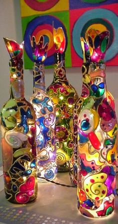 three colorful glass bottles sitting next to each other on top of a table in front of a painting