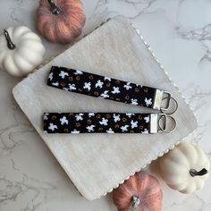 two black and white keychains sitting on top of a table next to pumpkins