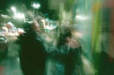 blurry photograph of people walking down the street at night