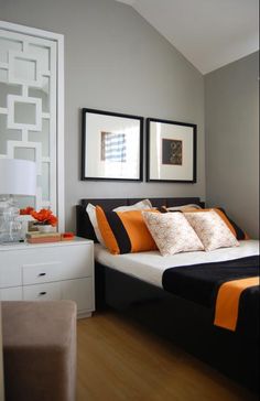 a bed with orange and black pillows in a bedroom