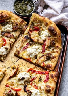 the pizza is cut into four pieces and ready to be served with pesto sauce