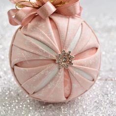 a pink ornament sitting on top of a glitter covered surface with a bow