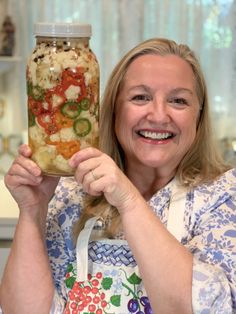 a woman holding up a jar filled with food