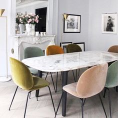 a marble dining table surrounded by chairs in a room with white walls and flooring