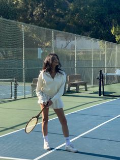 a woman standing on a tennis court holding a racquet in one hand and looking up at the sky