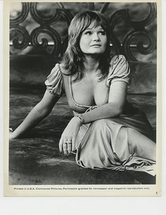 an old black and white photo of a woman sitting on the ground with her legs crossed