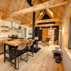 an open concept kitchen and dining area with wood flooring, exposed beams, and vaulted ceiling