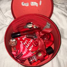 an open red heart shaped box filled with valentine's day items on a bed