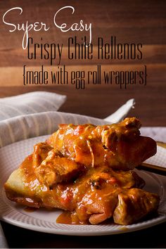 a white plate topped with meat covered in gravy on top of a wooden table