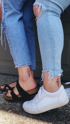 two people standing next to each other with tattoos on their ankles and feet, both wearing sandals