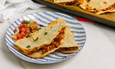 two quesadillas on a blue and white plate next to a baking pan