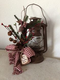 an old fashioned lantern is decorated with greenery, berries and pine cones for christmas