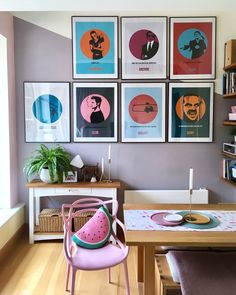 a dining room table with chairs and pictures on the wall above it, including watermelon slices