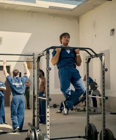 a man in blue jumps into the air while working on a pull - up machine