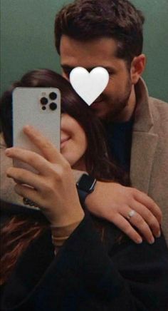 a man and woman taking a selfie with a heart on their forehead, in front of a cell phone