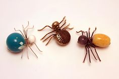 three spider figurines sitting next to each other on top of a white surface