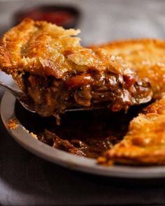 a piece of meat pie on a plate with a fork sticking out of the pie