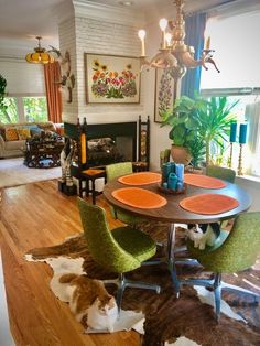 a cat laying on the floor in front of a table with chairs and a rug